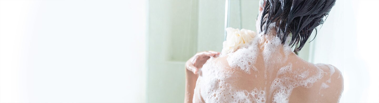 Mujer aromatizando su piel mientras toma una ducha Mujer aromatizando su piel mientras toma una ducha
