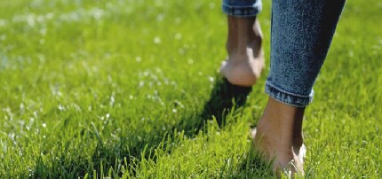 Haz pequeños ejercicios de estiramiento para los pies Pies descalzos caminando sobre un campo verde